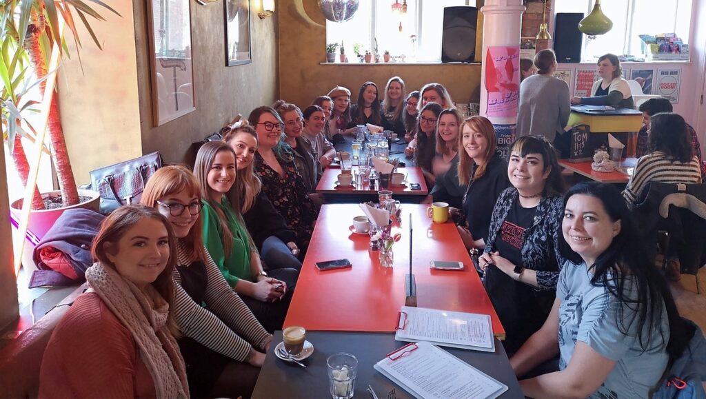 A large group of women sat around a restaurant table