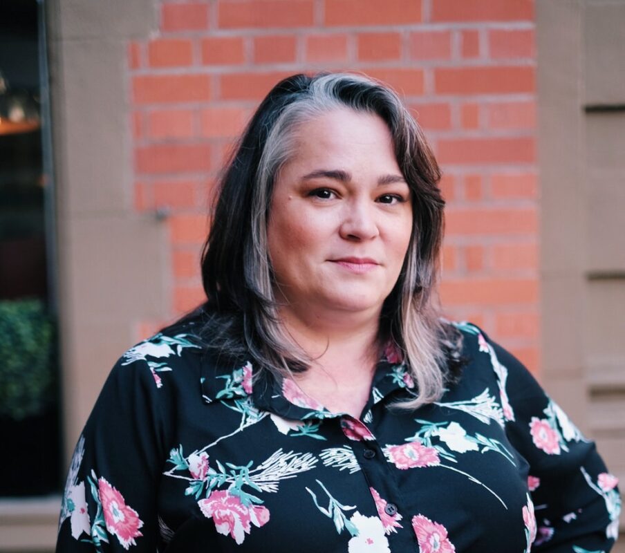 A portrait of Jennifer Calland standing in front of a building